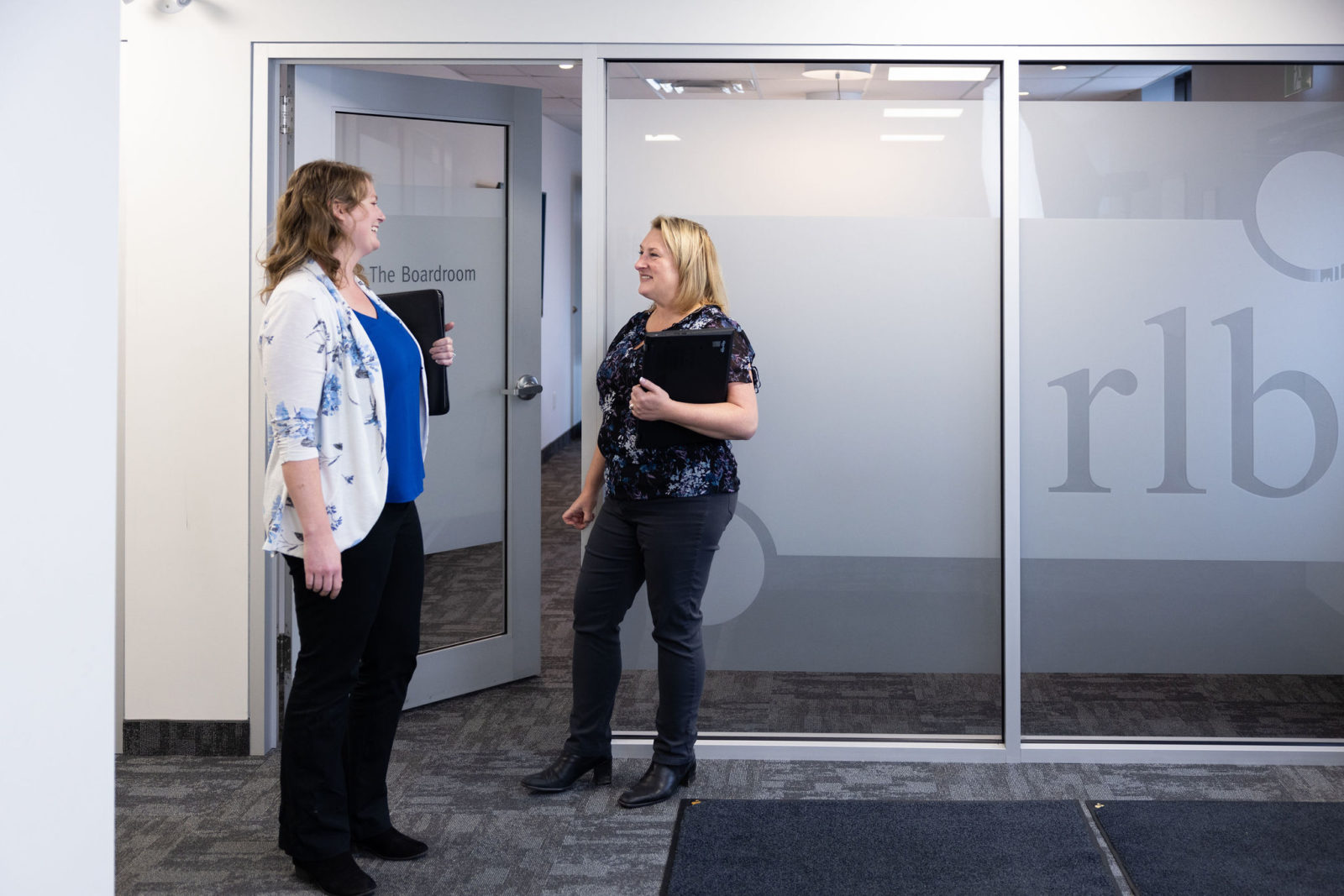 People standing outside of a meeting room having a conversation at the RLB Orangeville Office
